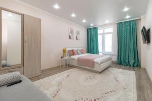 een slaapkamer met een bed en een raam met groene gordijnen bij Апартаменты в ЖК Only Sun - 3 in Astana