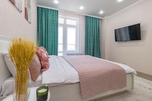 een slaapkamer met een bed met groene gordijnen en een tv bij Апартаменты в ЖК Only Sun - 3 in Astana