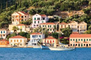 two boats sitting in the water in front of houses at The Bay House in Vathi, Ithaka