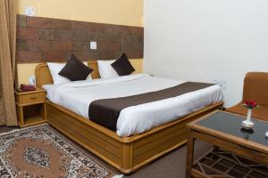 1 dormitorio con 1 cama grande con marco de madera en The Hill Paradise, en Almora