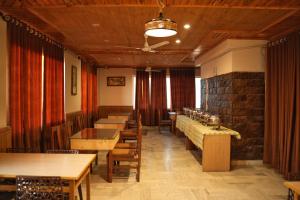 un restaurante con mesas y sillas de madera y una pared de ladrillo en The Hill Paradise, en Almora