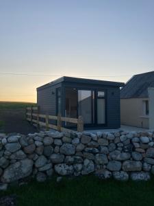 a house with a stone wall in front of it at Donegal Luxury Pods in Gweedore