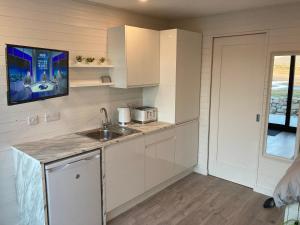 a kitchen with white cabinets and a sink at Donegal Luxury Pods in Gweedore
