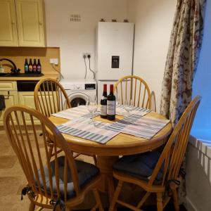 una mesa de madera con botellas de vino y sillas en la cocina en Killean Farmhouse Cottages, 