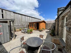 eine Terrasse mit einem Tisch und Stühlen sowie ein Gebäude in der Unterkunft Lands End Hostel and B&B in Sennen