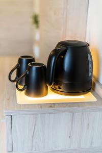 a tea kettle and two mugs on a counter at Hökis-Zimmervermietung 7 in Brande-Hörnerkirchen