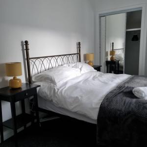 1 dormitorio con 1 cama con sábanas blancas y espejo en Killean Farmhouse Cottages, 