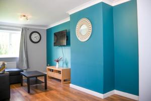 una sala de estar con una pared azul en 2ndHomeStays- Willenhall-A Serene 3 Bed House with a Garden View-Suitable for Contractors and Families-Sleeps 9 - 7 mins to J10 M6 and 21 mins to Birmingham en Willenhall