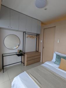 - une chambre avec un grand lit et un miroir dans l'établissement Breezy Tagaytay Condo, à Tagaytay