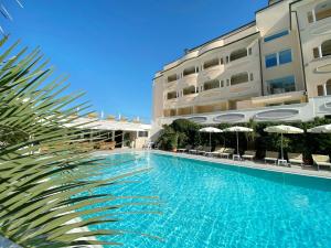a swimming pool in front of a building at Hotel Derby Exclusive in Milano Marittima