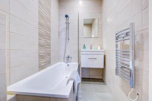 a white bathroom with a tub and a sink at Spacious and Modern 1 Bed 1 Bath Apartment in the Heart of Eastbourne in Eastbourne