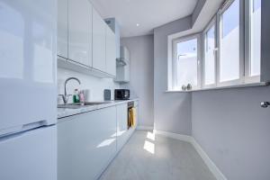a kitchen with white cabinets and a window at Spacious and Modern 1 Bed 1 Bath Apartment in the Heart of Eastbourne in Eastbourne