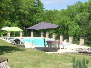 una piscina con sombrilla, mesa y sillas en Totally Secluded Stone Cottage with Private Pool, 2 acres of Garden and Woodland, en Paussac-et-Saint-Vivien