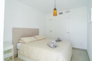 a white bedroom with a bed with towels on it at Solymar Sun & Beach Deluxe Apartments in Nerja