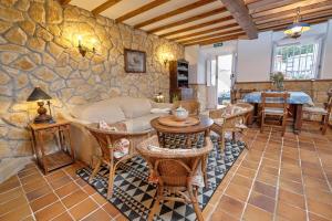 sala de estar con pared de piedra, mesa y sillas en Casona del Sol El Retorno I, en Lastres