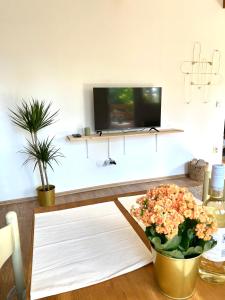 a living room with a tv and a table with flowers at Erdősor út Vendégház in Piliscsaba