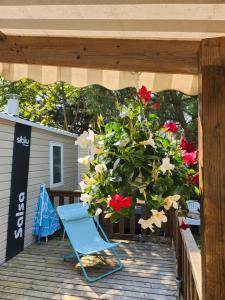 a blue chair sitting on a deck with flowers at Mobile-home Bonne -Anse Plage in Les Mathes