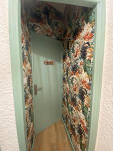 - un couloir avec une porte ornée d'un papier peint floral dans l'établissement La Suite des Platanes, à Perpignan