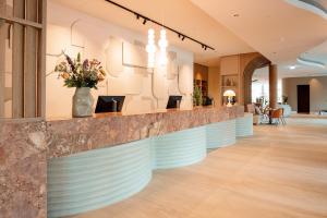 a lobby with a long counter with flowers at Van der Valk Hotel Eindhoven-Best in Best