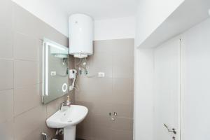 W białej łazience znajduje się umywalka i lustro. w obiekcie New Apartment at New Bazaar - Tirana City Center w Tiranie