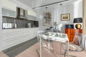a kitchen with white cabinets and a glass table at Central Apartments-Gdansk&Sz7/5 in Gdańsk