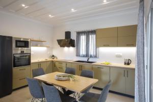 cocina con mesa de madera y sillas azules en Panoutsis Villa Vista, en Sívros