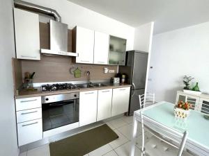 - une cuisine avec des placards blancs, une table et une cuisinière dans l'établissement appartamento la torre, à Pietrasanta