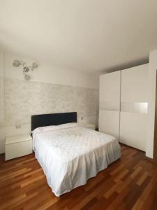 Schlafzimmer mit einem weißen Bett und Holzboden in der Unterkunft Casa vacanze Le Gardenie in Conegliano