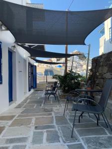 eine Terrasse mit Stühlen, einem Tisch und einem Sonnenschirm in der Unterkunft Zinas pension in Chora, Ios