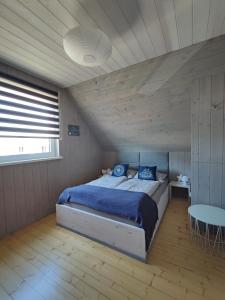 Schlafzimmer mit einem Bett mit blauer Bettwäsche und einem Tisch in der Unterkunft Słoneczny Raj Apartamenty Domki apartamentowe in Sarbinowo