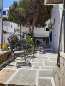 a patio with chairs and tables and a tree at Zinas pension in Ios Chora
