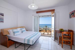 a bedroom with a bed and a balcony with the ocean at Sunrise Apartments in Sfakaki