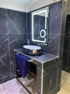 ein Bad mit einem Waschbecken und einem Spiegel in der Unterkunft Chez Lilie Maison d'hôtes à Saly in Saly Portudal