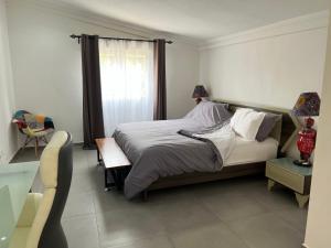 1 dormitorio con cama, mesa y ventana en Chez Lilie Maison d'hôtes à Saly en Saly Portudal