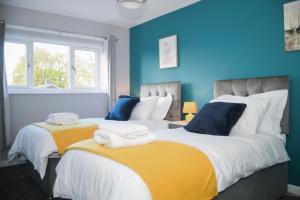 two beds in a room with blue and yellow at 2ndHomeStays- Willenhall-A Serene 3 Bed House with a Garden View-Suitable for Contractors and Families-Sleeps 9 - 7 mins to J10 M6 and 21 mins to Birmingham in Willenhall