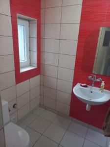 baño con lavabo y pared roja en Agroturystyka Kaszuby, en Parchowo