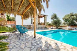 a swimming pool with two chairs and a straw umbrella at Villa Luna in Kavála