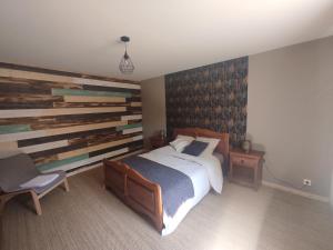 1 dormitorio con 1 cama grande y pared de madera en Gîte des trois petits oiseaux, en Picarreau