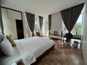 a bedroom with a bed and a desk and windows at The Dream Villa Best Lake View in Xuan An