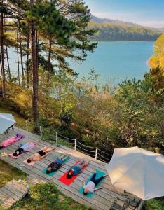 a group of people laying on a deck near a lake at The Dream Villa Best Lake View in Xuan An