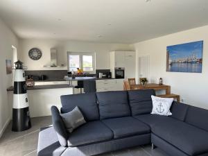 ein Wohnzimmer mit einem blauen Sofa und einer Küche in der Unterkunft Ferienhaus RELAX in Büsum
