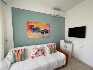 a living room with a white couch and a painting at Cozy Beachfront Maisonette Offers Panoramic Views of Sea in Metókhion Konstamonítou