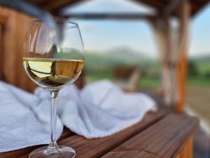a glass of white wine sitting on a wooden table at Lackowa Chill and Rest domki z balią Krynica Zdrój in Krynica Zdrój