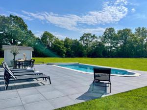 eine Terrasse mit einem Tisch und Stühlen neben einem Pool in der Unterkunft La Normande - Piscine chauffée in Saint-Symphorien