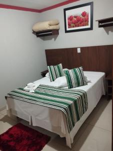 Turis Hotel في دورادوس: غرفة نوم عليها سرير وبطانية مخططة