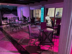 um grupo de mesas e cadeiras num quarto com luzes cor-de-rosa em Chez Lilie Maison d'hôtes à Saly em Saly Portudal