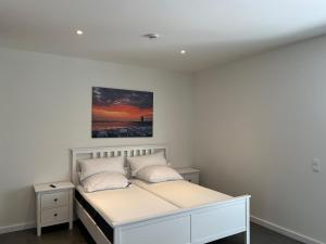 ein Schlafzimmer mit einem weißen Bett und einem Gemälde an der Wand in der Unterkunft Ferienhaus RELAX in Büsum