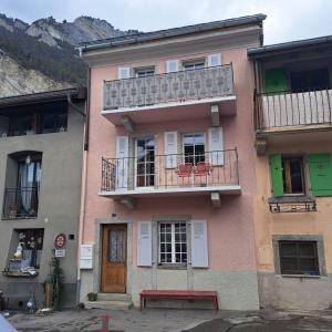 różowy budynek z balkonem i stołem na nim w obiekcie La Vie Eau Naturelle w mieście Sembrancher