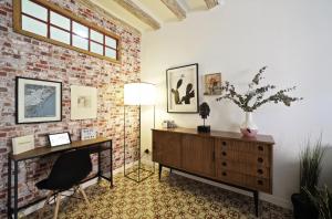 een woonkamer met een bakstenen muur, een bureau en een stoel bij Almodovar Apartment Barcelona in Barcelona