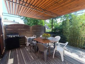 una terraza de madera con mesa, sillas y parrilla en Gîte Rosa et Jean-Jacques en Aigues-Mortes